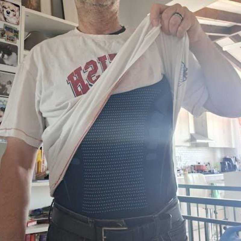 Klant Jan v.P. tilt zijn T-shirt op en laat het shaping shirt eronder zien