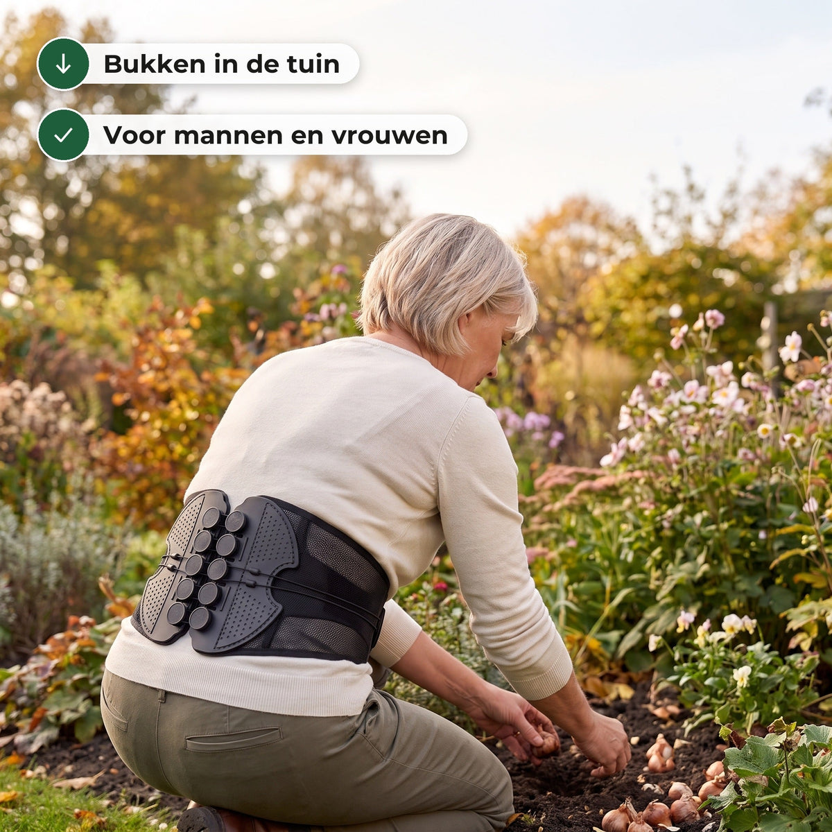 Vrouw van rond de 60 knielt in de tuin en plant bloembollen, met de rugbrace om