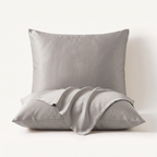 Set van twee satijnen kussenslopen in zilvergrijs, 60 bij 70 cm, met de envelopflap losjes over de voorste sloop gedrapeerd