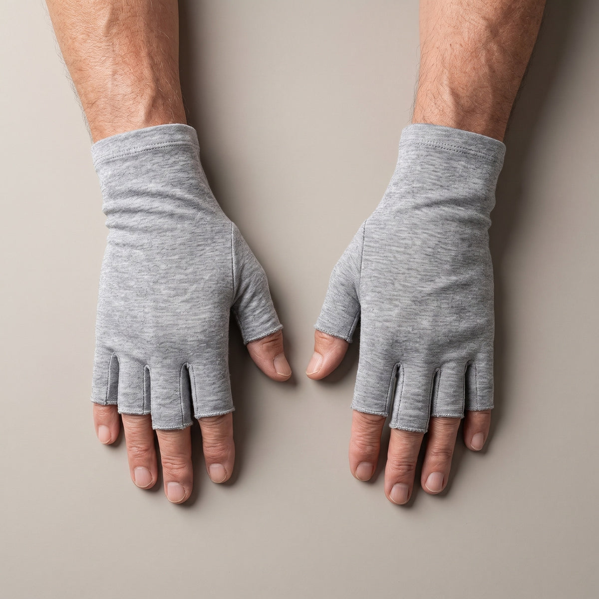 Handen van een oudere man met de lichtgrijze compressiehandschoenen, van boven gezien, vingertoppen vrij