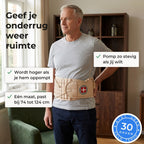 Man van rond de zestig staat in zijn woonkamer met de beige decompressiegordel opgepompt om zijn onderrug, zijn hand in zijn zij