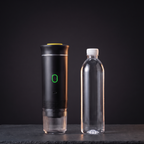 De espressomachine naast een flesje water van een halve liter, allebei even hoog, tegen een donkere achtergrond