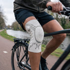 Fietser op een fietspad langs een gracht, kniebrace zichtbaar op de trappende knie