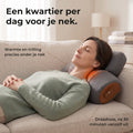 Vrouw van rond de 45 ligt ontspannen op een lichte bank met haar nek op het grijze nekstretchkussen met warmte, het losse hoofdkussen onder haar achterhoofd