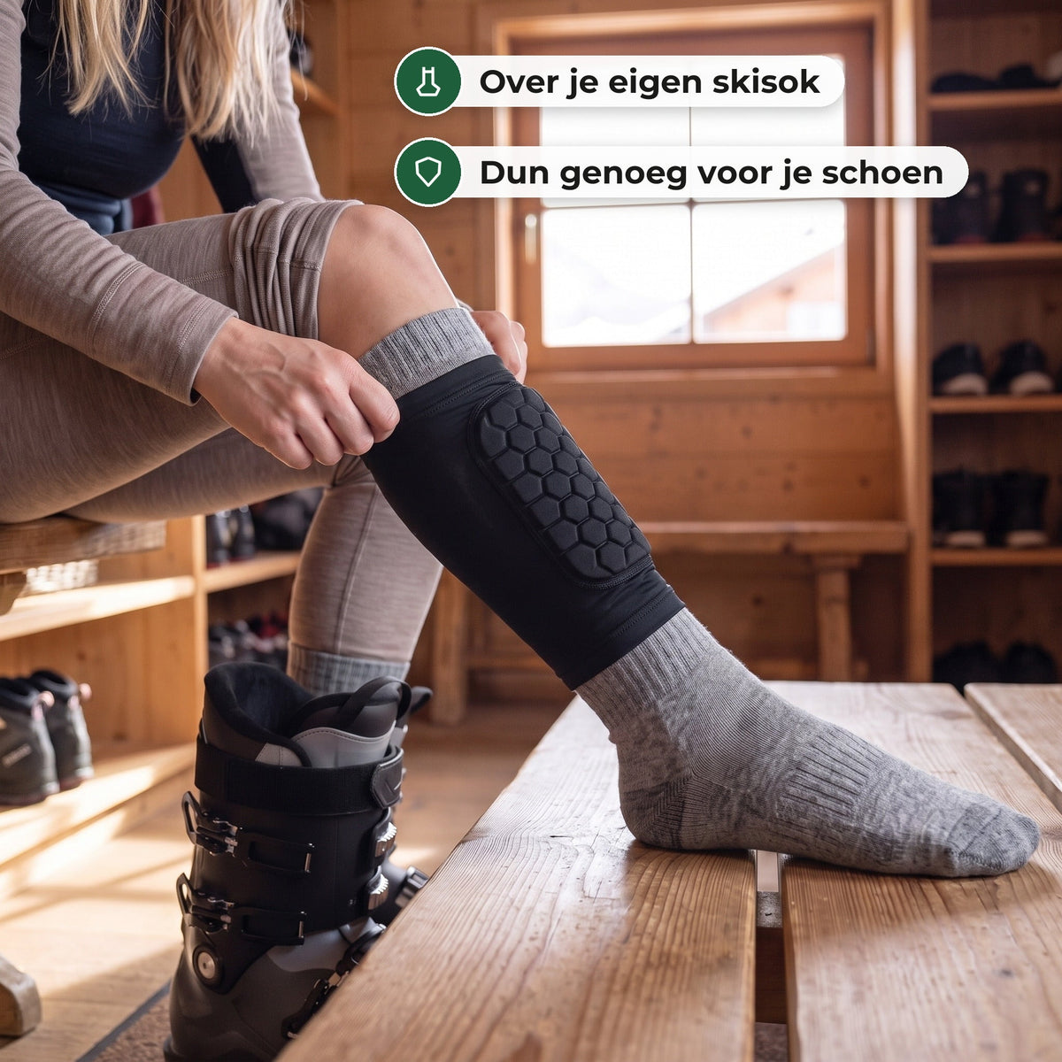 Vrouw in een houten skikelder trekt de korte zwarte scheenbeschermer met honingraatkussen over haar grijze skisok