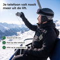 Skiër in de stoeltjeslift maakt een foto, zijn telefoon zit met een dun koord vast aan de koordrol op zijn rugzakband