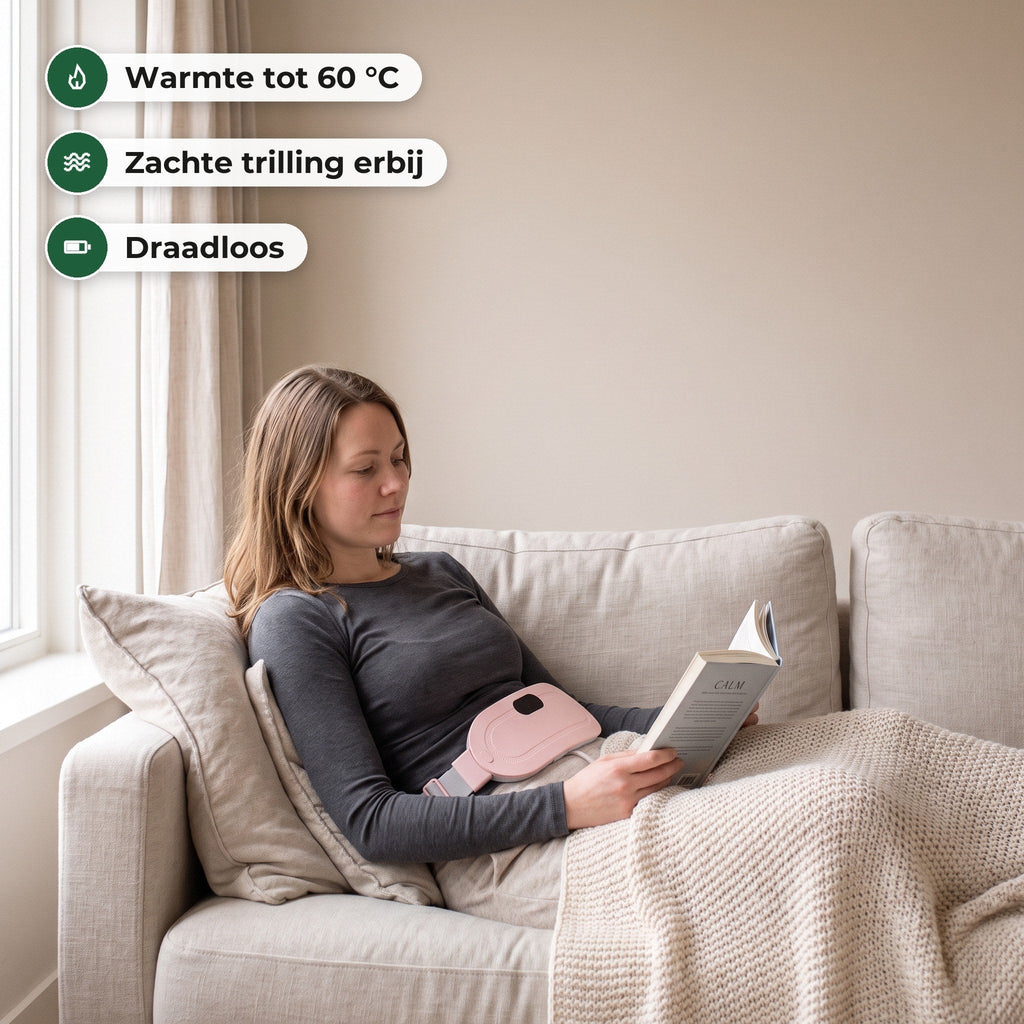 Vrouw ligt op de bank met een boek en een plaid en draagt de roze warmteband op haar buik