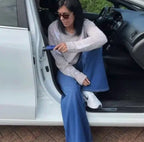 Vrouw stapt uit een witte auto terwijl ze zich vasthoudt aan de steungreep in de deurstijl