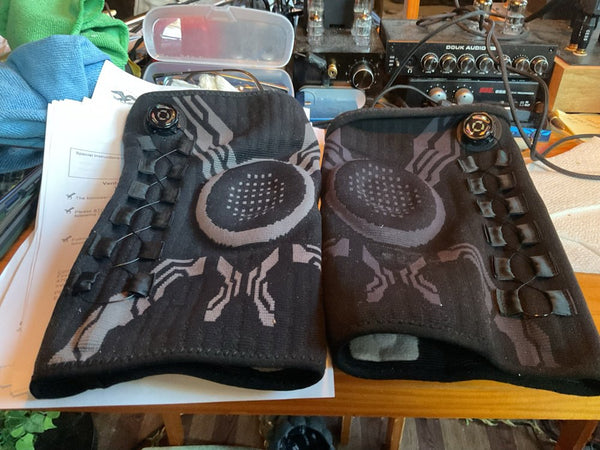 Foto van een koper: twee zwarte kniebraces met draaiknop op een bureau
