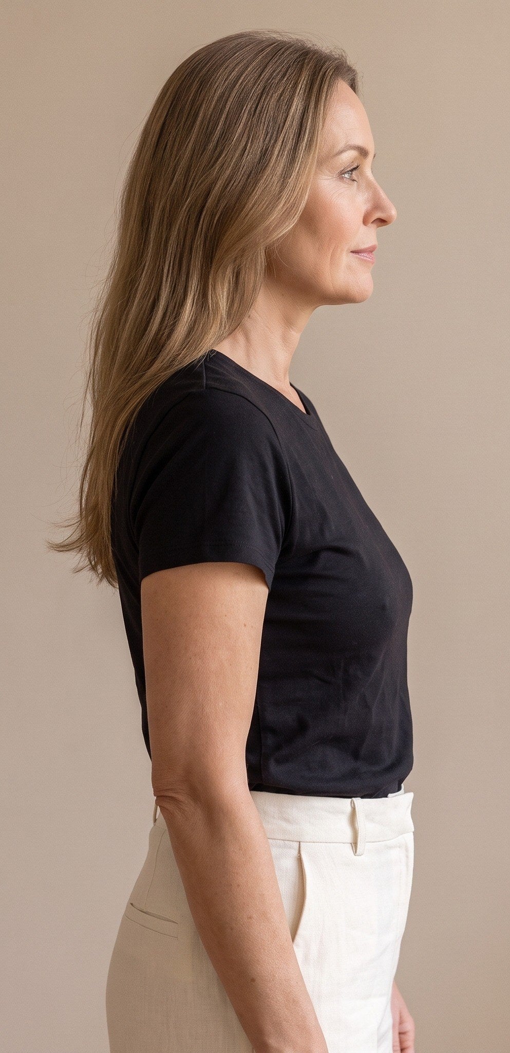 Vrouw van opzij in een zwart T-shirt met een oude bh eronder