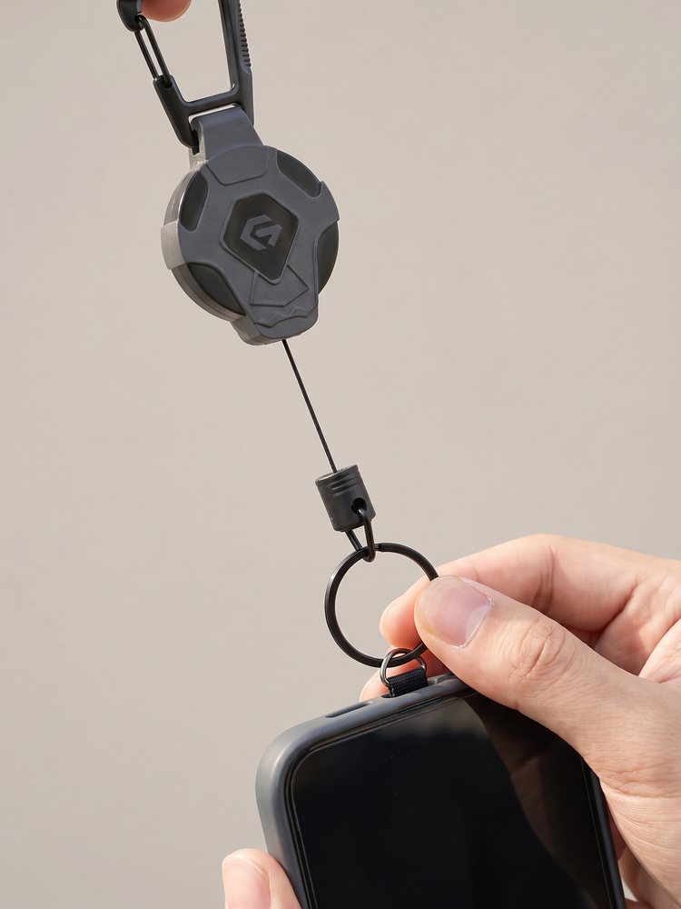 Hand klikt de ring van het koord aan het lipje onder de telefoon